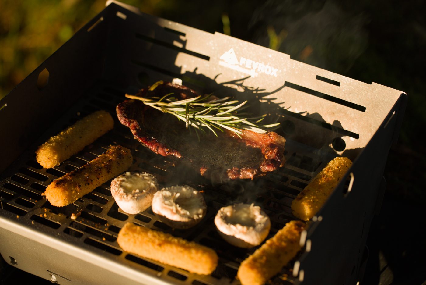 Steak with rosemary, sausages and stuffed mushrooms grilling on the Titan1 titanium grate